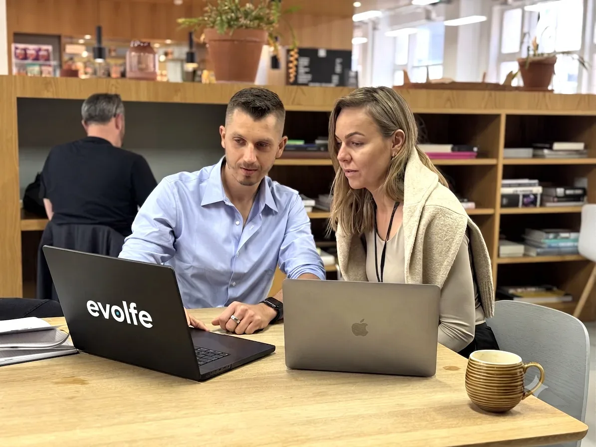 An Evolfe consultation with two people discussing their laptops at a shared table